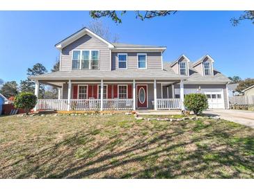 Charming two-story home featuring a welcoming front porch, gray siding, and a well-maintained lawn on a sunny day at 737 Wilkes Dr, Loganville, GA 30052
