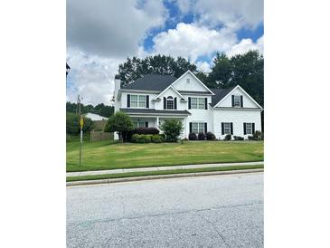 Charming two-story home featuring a manicured lawn and classic architectural details at 540 Langley Creek Dr, Loganville, GA 30052