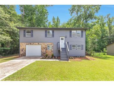 Charming two-story home with stone accents, landscaped front yard, and gray siding at 6906 Shangrila Way, Riverdale, GA 30296