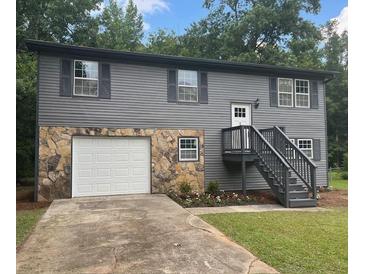 Charming two-story home featuring a stone facade, gray siding, and a well-maintained front yard with flower beds at 6906 Shangrila Way, Riverdale, GA 30296