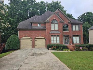 Traditional two-story brick home with a two-car garage, manicured lawn, and mature trees at 3930 Regal Oaks Dr, Suwanee, GA 30024