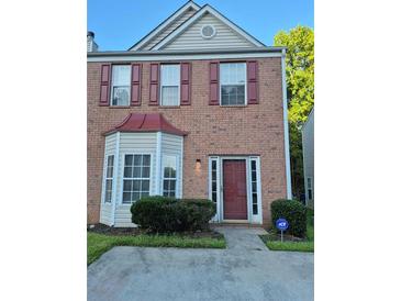 Charming two-story brick home with bay window, red shutters and a well maintained front yard at 5570 Hampton Ct, Atlanta, GA 30349