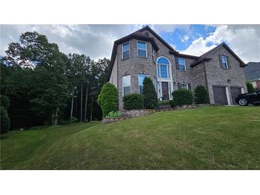 Two-story brick home with a well-manicured lawn, mature trees, and a two-car garage at 2819 Heritage Oaks Cir, Dacula, GA 30019