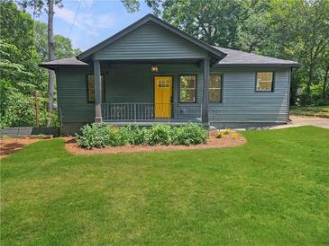 Charming exterior view of well-maintained home with inviting front yard and bright, welcoming, yellow front door at 1497 Elizabeth Ln, East Point, GA 30344