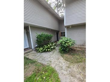 Modest home exterior featuring light siding and a small garden at 8562 Creekwood Way, Jonesboro, GA 30238