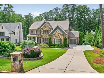 Beautiful stone and brick home with lush landscaping and a curved driveway at 6470 Long Island Nw Dr, Atlanta, GA 30328