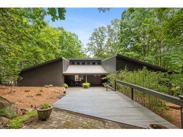 Charming home with a welcoming walkway, mature trees, and unique architectural details at 10775 Shallowford Rd, Roswell, GA 30075