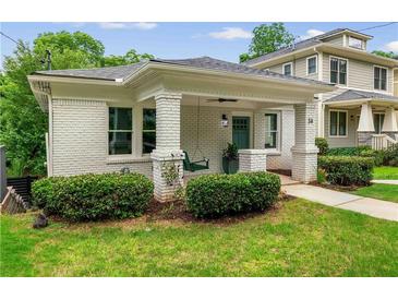 Charming bungalow featuring a covered front porch, swing, white brick, and manicured landscaping at 34 Montgomery Se St, Atlanta, GA 30317