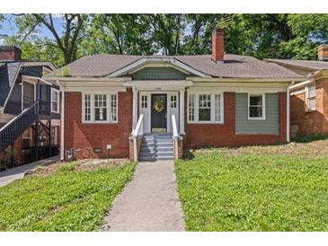 Charming brick home featuring a cozy front porch and well-manicured lawn at 1585 Olympian Sw Cir, Atlanta, GA 30310