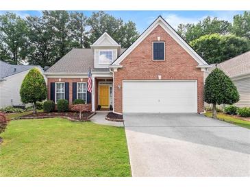 Charming brick home featuring a well-manicured lawn, attached two-car garage and inviting yellow front door at 3427 Hampreston Nw Way, Kennesaw, GA 30144