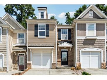 Charming townhome featuring a one car garage and neutral toned facade with black shutters and stone accents at 2130 Executive Dr, Duluth, GA 30096