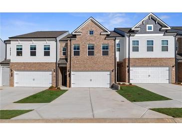 Charming townhome showcases a brick and siding exterior, complemented by an attached garage and well-manicured landscaping at 8207 Tiger Way, Riverdale, GA 30296