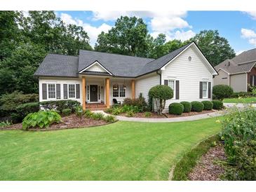 Charming one-story home featuring a lush lawn, manicured landscaping, and inviting front porch with wooden support columns at 6490 Ivey Hill Dr, Cumming, GA 30040