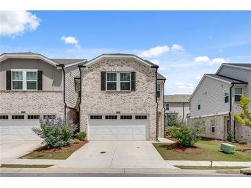 Charming two-story home with a two-car garage, brick facade, and landscaped front yard at 1542 Villageside Ct, Lawrenceville, GA 30043