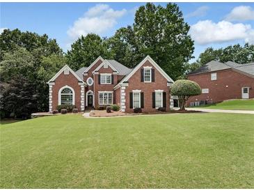 Charming brick home boasts a well-manicured lawn and mature trees, enhancing its curb appeal at 6630 Club Valley Ct, Suwanee, GA 30024