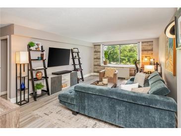 Bright living room featuring a plush blue sofa, modern shelving, and large windows with a lush green view at 2479 Peachtree Ne Rd # 201, Atlanta, GA 30305