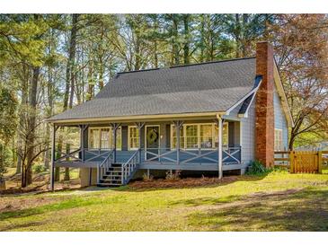 Charming blue home with a welcoming front porch and brick chimney, nestled among lush trees at 216 Hickory Way, Canton, GA 30115