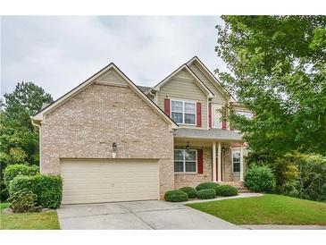 Charming two-story home featuring a brick facade, red shutters, a manicured lawn, and an attached two-car garage at 3439 Tupelo Trail, Auburn, GA 30011