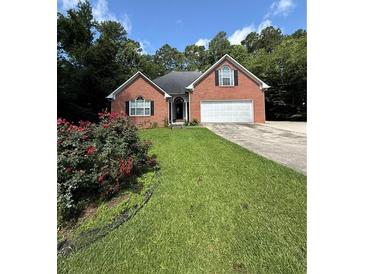 Charming single-story brick home featuring an attached two-car garage and a well-maintained lawn with lovely flower bushes at 709 Stonehenge Pl, Jonesboro, GA 30236