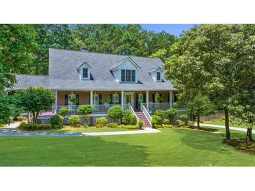 Charming brick home featuring a welcoming front porch, lush landscaping, and mature trees at 340 Helens Manor Dr, Lawrenceville, GA 30045