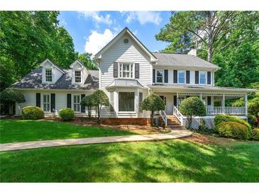 Beautiful two-story home with a covered front porch, mature trees, and manicured landscaping at 440 Junction Trak, Roswell, GA 30075