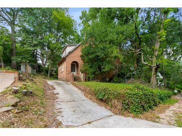 Charming brick home with arched entryway and mature trees lining the driveway at 1200 Mansfield Ne Ave, Atlanta, GA 30307