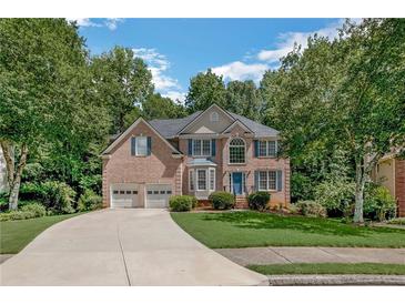 Charming two-story brick home with a two-car garage, lush landscaping, and a curved driveway at 1625 Hawkins Cove Trl, Roswell, GA 30076