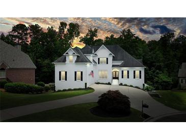 Beautiful white home featuring manicured lawns, a circular driveway, and mature trees under a colorful sunset at 6017 Chestatee Creek Nw Ct, Acworth, GA 30101