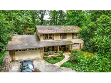 Charming two-story home nestled amongst mature trees with an attached garage and long drive at 3841 Brooklawn Ne Ct, Brookhaven, GA 30319
