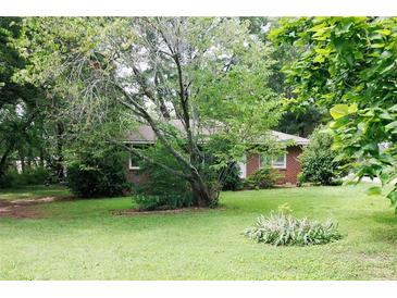 Cozy single-story brick home featuring a well-maintained lawn and mature trees at 127 Perry St, Loganville, GA 30052