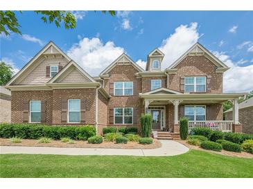 Charming brick home featuring manicured lawn, lush shrubs and a welcoming front porch at 5515 Cheatam Ave, Cumming, GA 30040