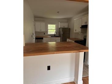 Charming kitchen featuring white cabinets, stainless steel appliances, wood countertops and a bright window at 2037 Brannen Se Rd, Atlanta, GA 30316