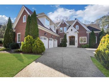 Stunning brick home featuring a three-car garage, mature landscaping, and a beautiful stone entryway at 821 Camden Park Ct, Atlanta, GA 30342