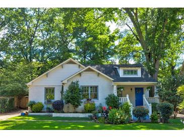 Charming home with white brick, blue door, lush lawn and mature trees at 135 Martha Ne Ave, Atlanta, GA 30317