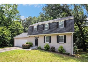 Charming two-story home featuring a gray brick facade, black shutters, and a well-maintained front lawn at 120 E Cainwood E Ct, Atlanta, GA 30349