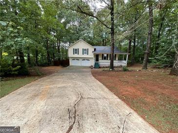 Charming yellow two-story home with a two-car garage and inviting front porch surrounded by lush trees at 48 Glenhaven Ct, Douglasville, GA 30134