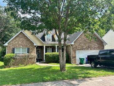 Charming brick home featuring a well-manicured lawn, mature trees, and an attached two-car garage at 6941 Roane Ct, Lithonia, GA 30038