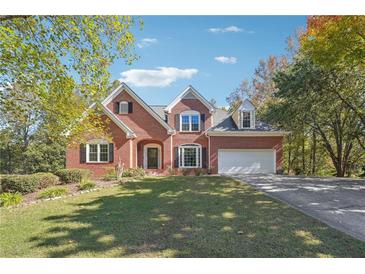 Charming brick home featuring a well-manicured lawn, mature trees, and a two-car garage at 2335 Corbett Ct, Powder Springs, GA 30127