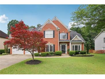 Charming two-story brick home featuring a manicured lawn, mature landscaping, and a three-car garage at 2009 Mclain Nw Rd, Acworth, GA 30101