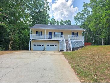 Inviting home with a charming front porch and a two-car garage nestled among mature trees at 294 Spring Leaf Dr, Dallas, GA 30157