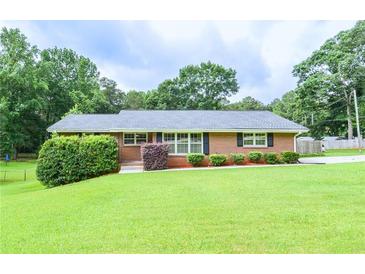Charming one-story brick home with a well-manicured lawn, shrubs and black shutters at 879 Old Tucker Rd, Stone Mountain, GA 30087
