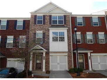 Brick townhome featuring a front-entry garage, white trim, and symmetrical window design at 2199 Landing Walk Dr, Duluth, GA 30097