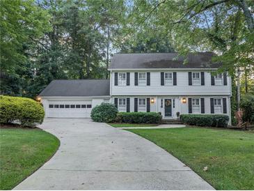 Traditional two-story home featuring a lush landscaped lawn, a symmetrical façade, and a long driveway to attached garage at 3609 Meadow Chase Dr, Marietta, GA 30062