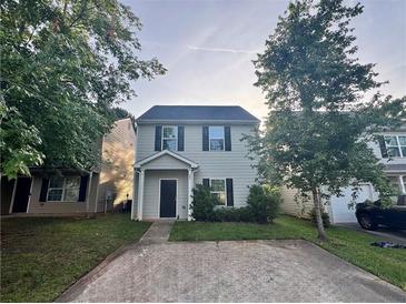 Charming two-story home featuring a cozy front porch, and a spacious driveway surrounded by mature trees at 241 Coral Cir, Mcdonough, GA 30253