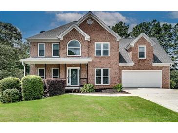 Charming brick home with two-car garage, manicured lawn, and inviting covered front porch at 1226 Kelly Nelson Ct, Lawrenceville, GA 30043