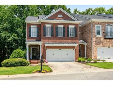 Charming red brick townhome with manicured lawn, attached two car garage, and classic architectural details at 3401 Village Green Dr, Roswell, GA 30075