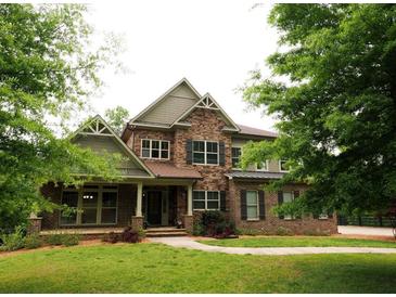 Stunning two-story home featuring a stone and brick facade, complemented by a lush green lawn and mature trees at 2845 Echols Road Rd, Cumming, GA 30041