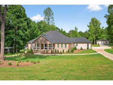 Beautiful single-story home boasts manicured lawn and inviting front porch, nestled amongst mature trees at 332 Mount Zion Rd, Oxford, GA 30054