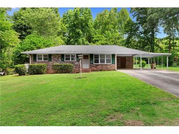 Charming brick home with a well-maintained lawn, mature trees, and a covered carport at 501 Samaritan Dr, Cumming, GA 30040