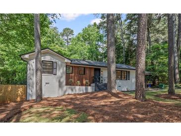 Charming single-story home features a beautifully painted brick facade, modern wood accents, and lush landscaping at 2238 Pinecliff Ne Dr, Atlanta, GA 30345